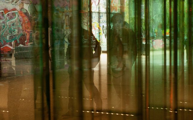 Two figures seen through a material walking in a graffiti street