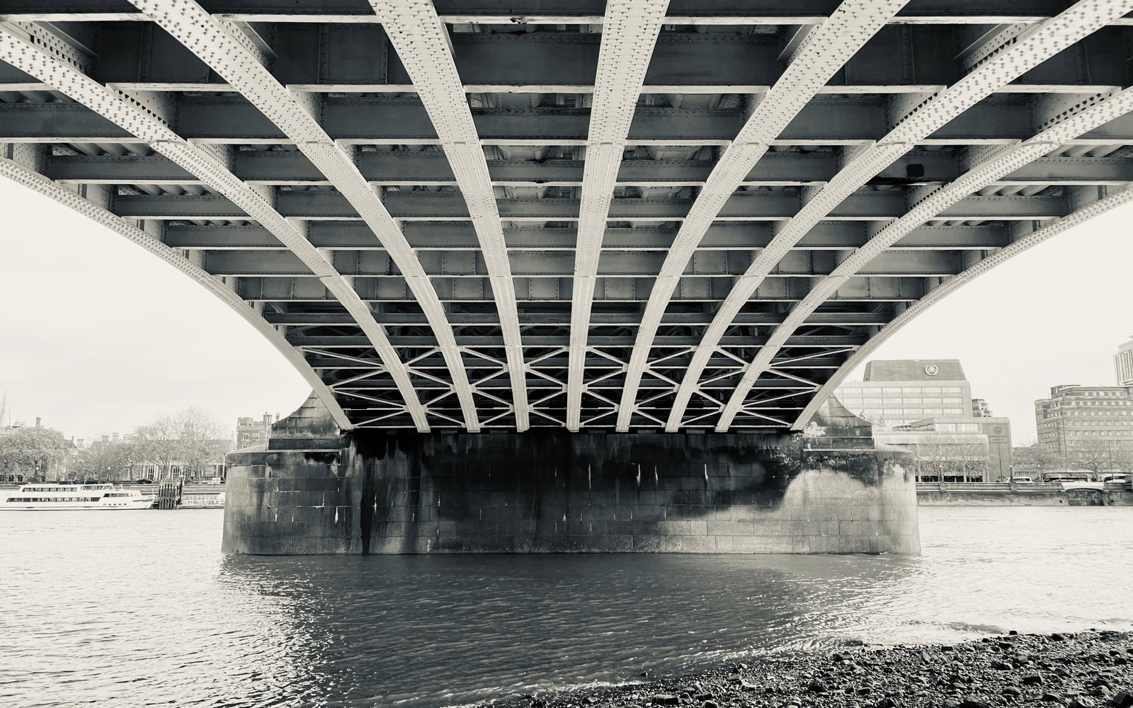 Black and white photograph of the underside of an industrial river bridge.