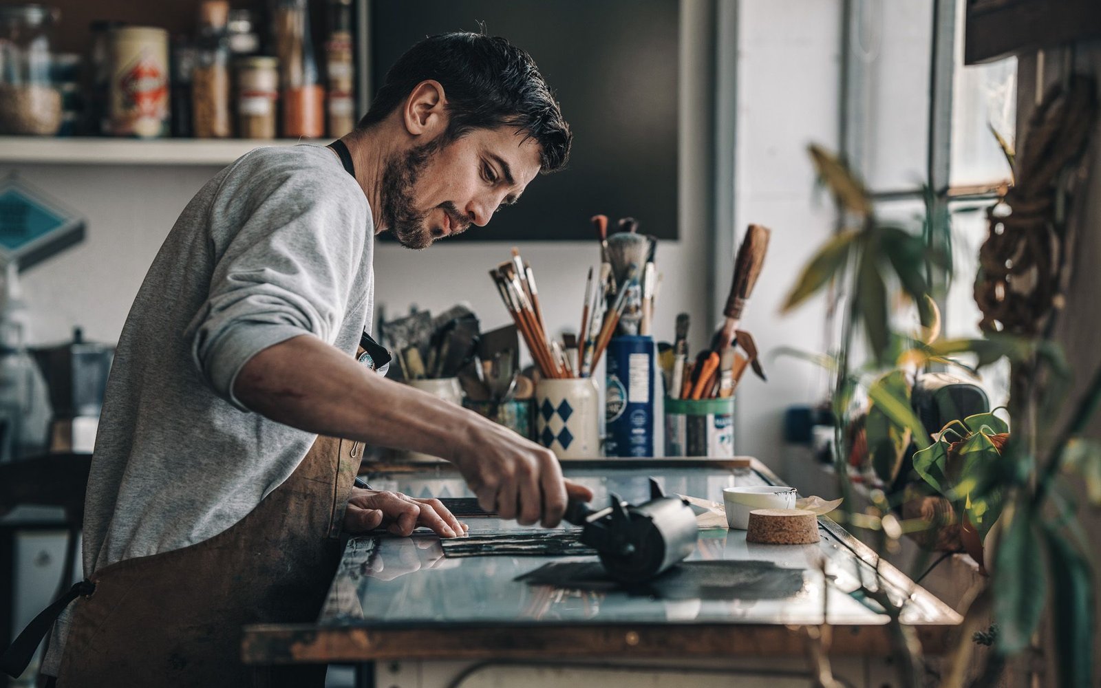 Alex Booker creates art in his studio, surrounded by various tools and materials, focused on his work.