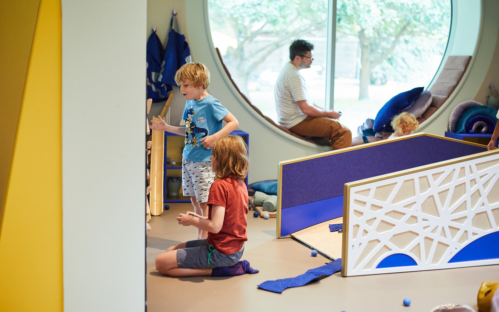 Two children talking in ArtPlay Pavilion with miniature wooden bridge in background