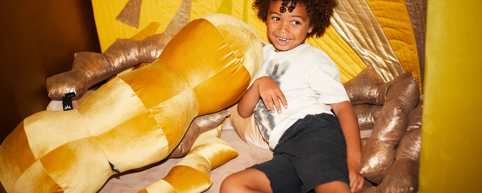 Child lying amongst gold and yellow cushions