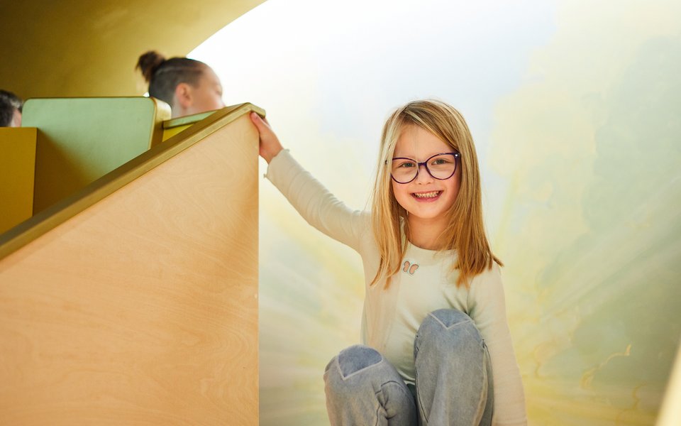A girl at the top of a slide smiling