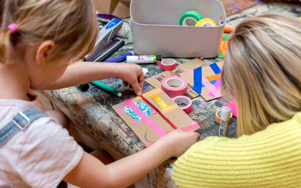 A girl and a woman sit at a table crafting