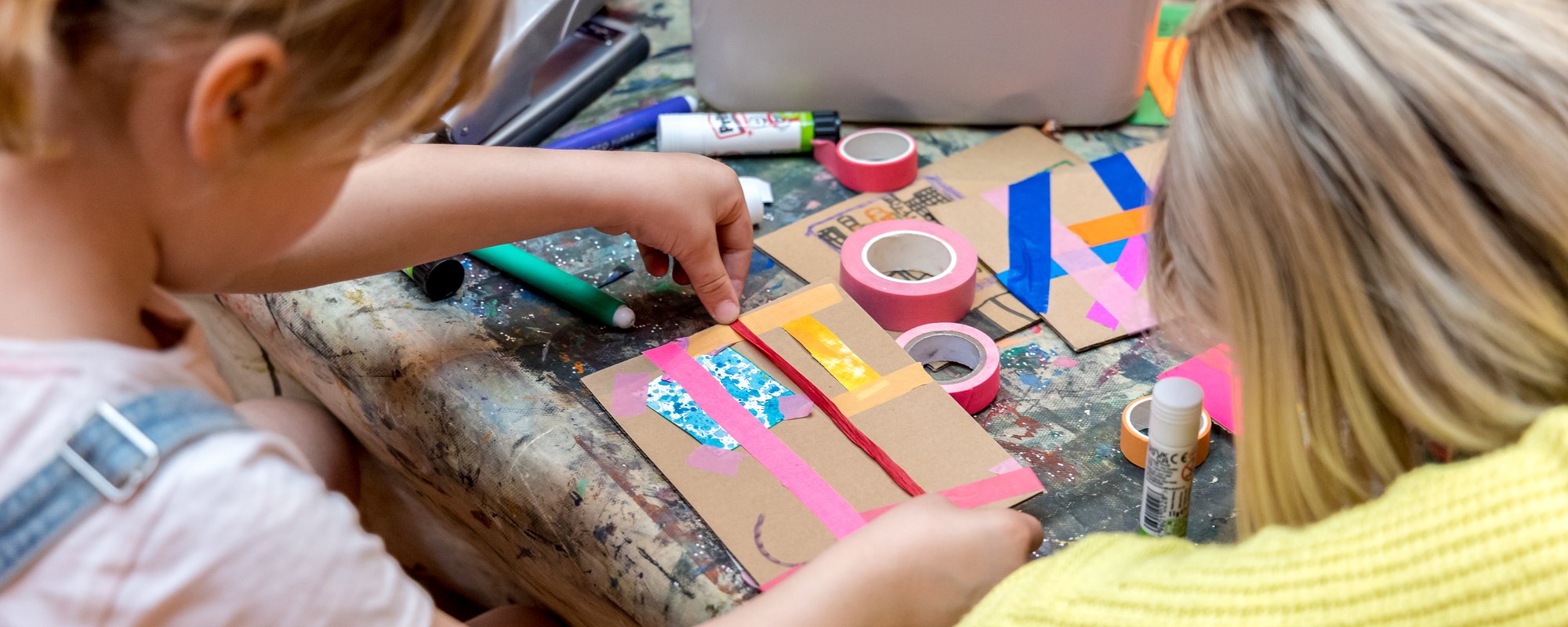 A girl and a woman sit at a table crafting