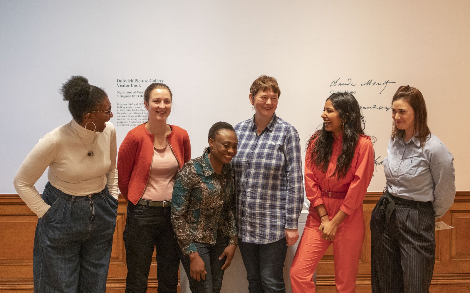 A group of people stand with arms around each others shoulders for a photograph