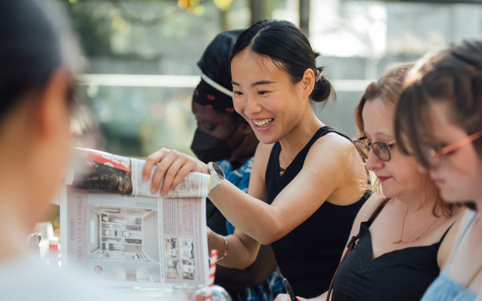 A group of people sit at a table crafting outside.