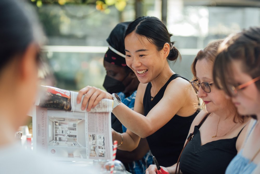 A group of people sit at a table crafting outside.