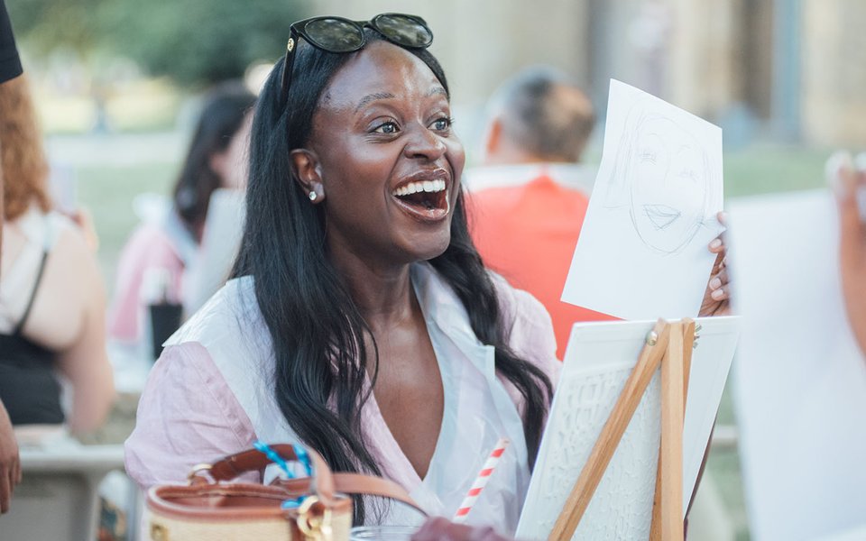 A woman sat in front of an easel looking surprised