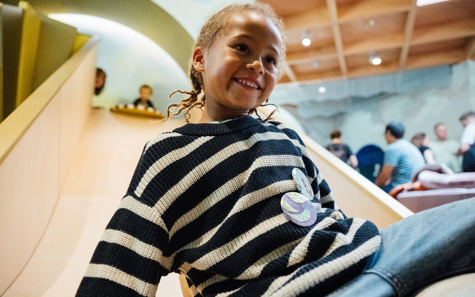 A boy smiles while going down a slide inside the ArtPlay Pavilion