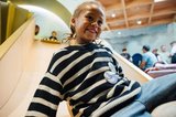 A boy smiles while going down a slide inside the ArtPlay Pavilion