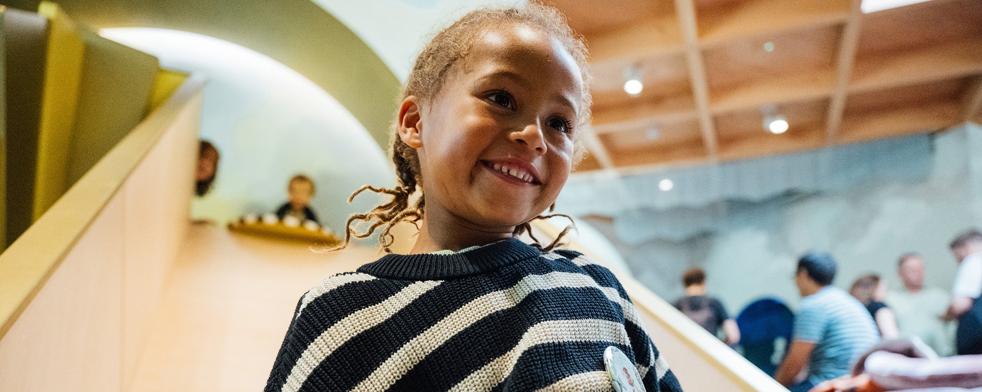 A boy smiles while going down a slide inside the ArtPlay Pavilion
