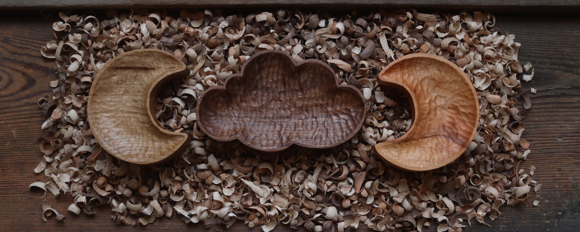 A wooden carved cloud shaped bowl centre with two crescent moon bowls either side.