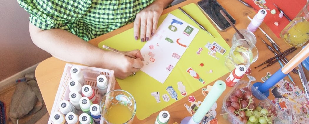 A person sat at a table designing charms for a necklace.