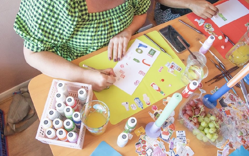 A person sat at a table designing charms for a necklace.