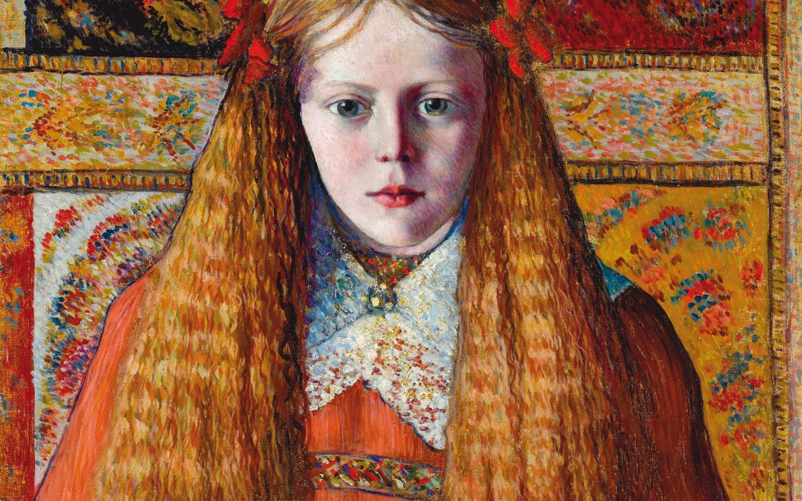 Portrait of a girl with long red hair wearing a red dress with a white lace collar. The background looks like a patterned tapestry with different coloured squares.