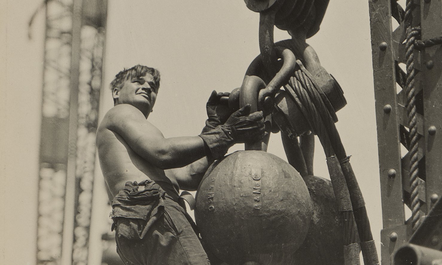 A man stands on a large chain suspended in the air