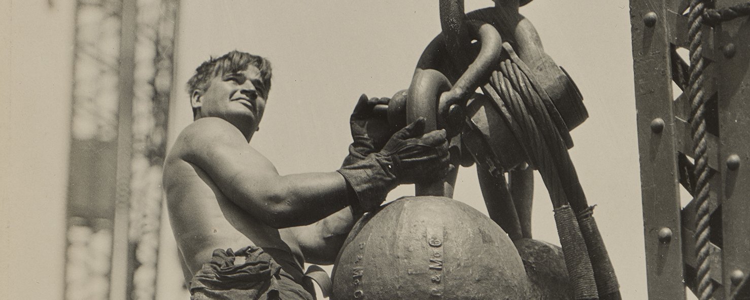 A man stands on a large chain suspended in the air