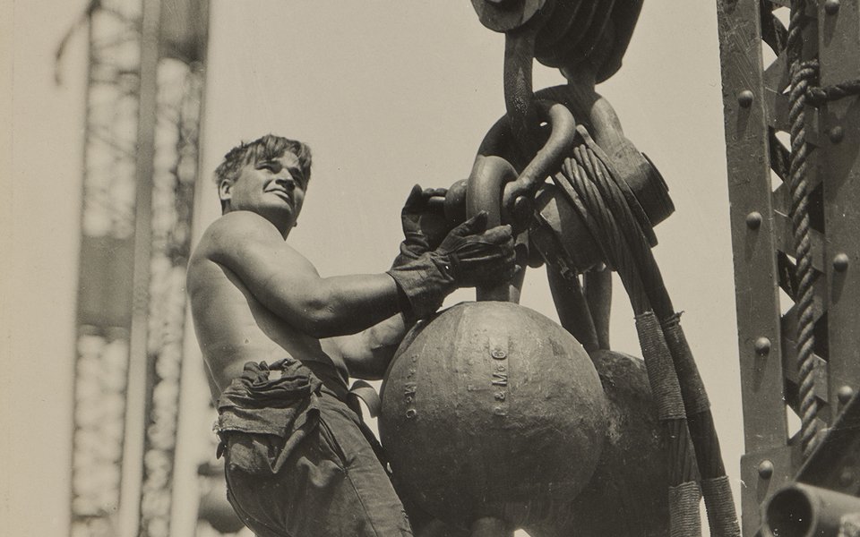A man stands on a large chain suspended in the air