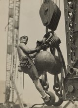 A man stands on a large chain suspended in the air