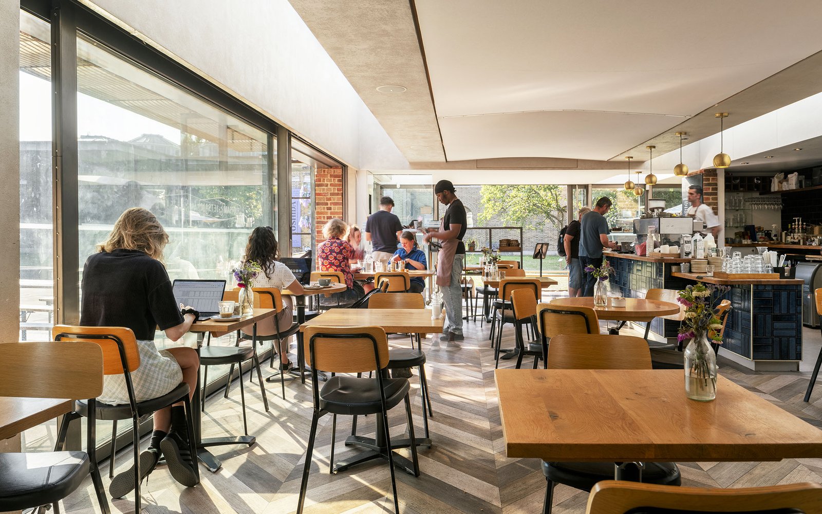 Interior of a cafe with table and chairs, bar to left and wall of windows to left.