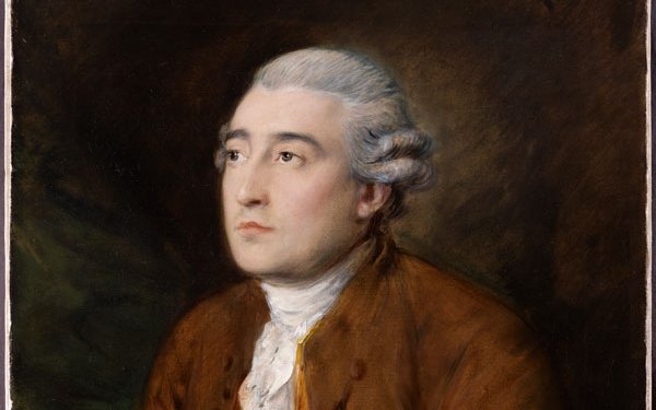 Portrait of a man with white wig, orange jacket and white shirt leaning on a table looking out to the right.