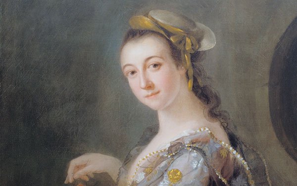 Portrait of a woman with a flowing dress with floral pattern holding a basket which she is pulling cherries from while looking out at the viewer.