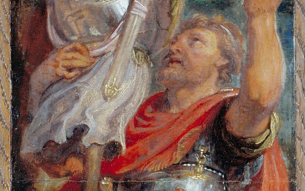 A man in Roman armor with a red gold trimmed cloak holds up an empty suit of armor in triumph.