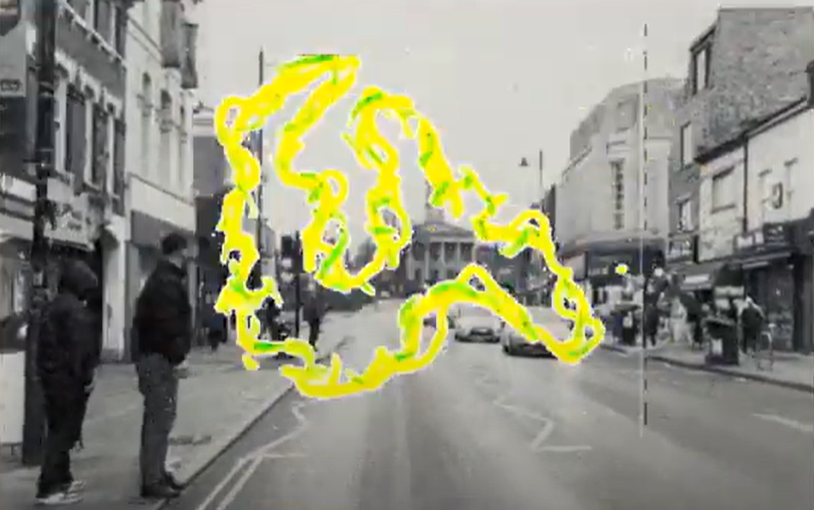 Clip from a film showing a bright yellow and green shape over a black and white photo of a street.