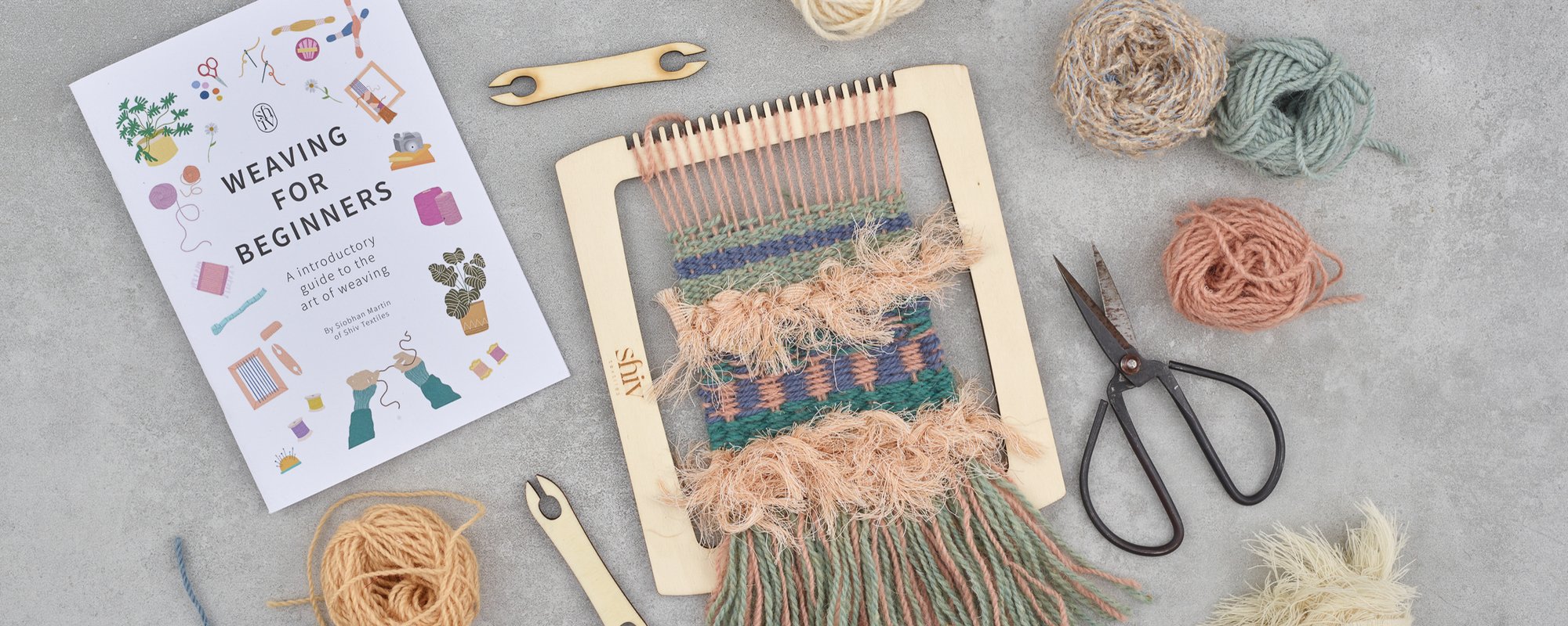 A weaving kit featuring scissors, colorful yarn, and additional crafting tools arranged neatly on a table.