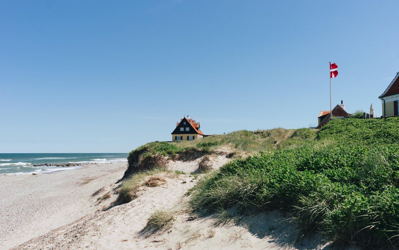 A beach with high dunes and a red house