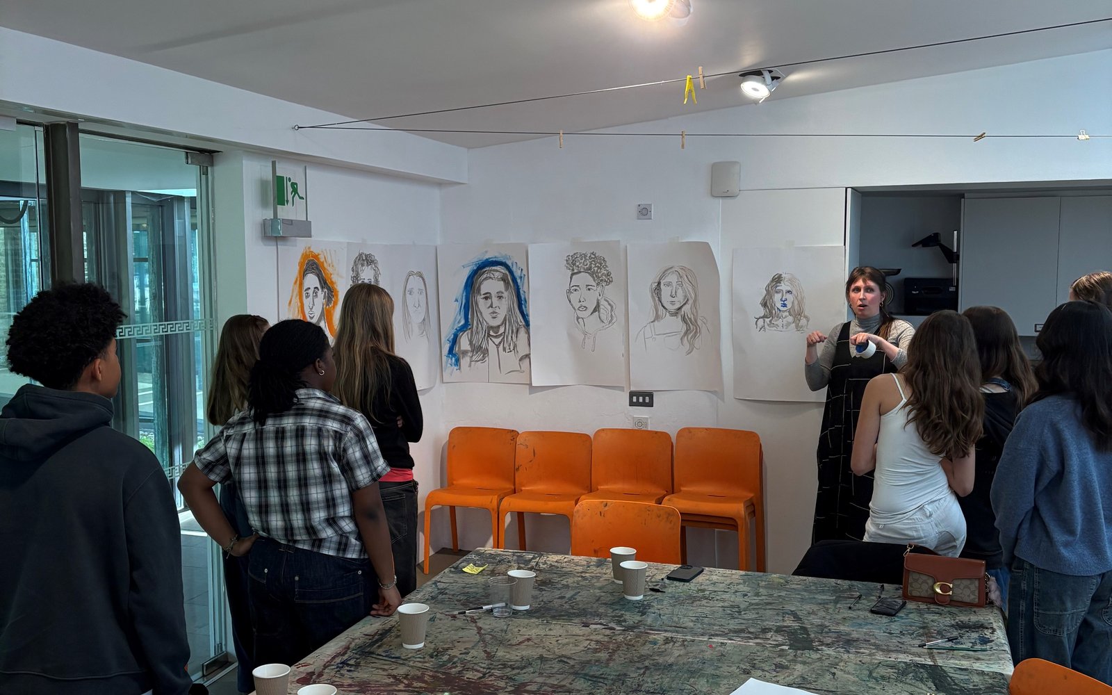 Group of young people in an art studio with portraits they have created on the walls.
