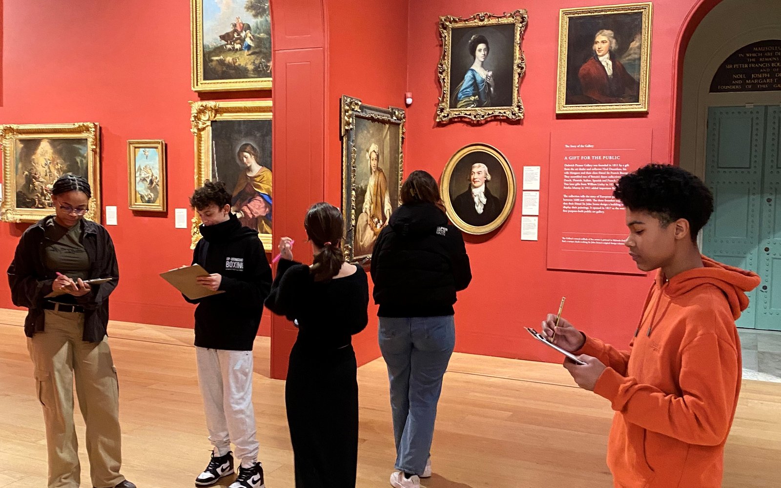 Group of young people stood in the gallery space.
