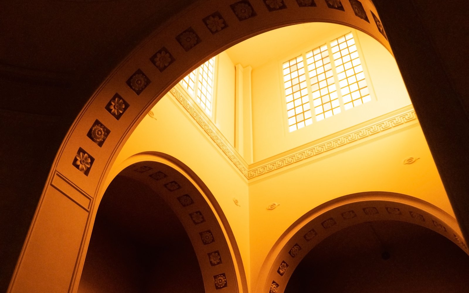 An arched interior of a mausoleum with skylight windows with yellow coloured glass.