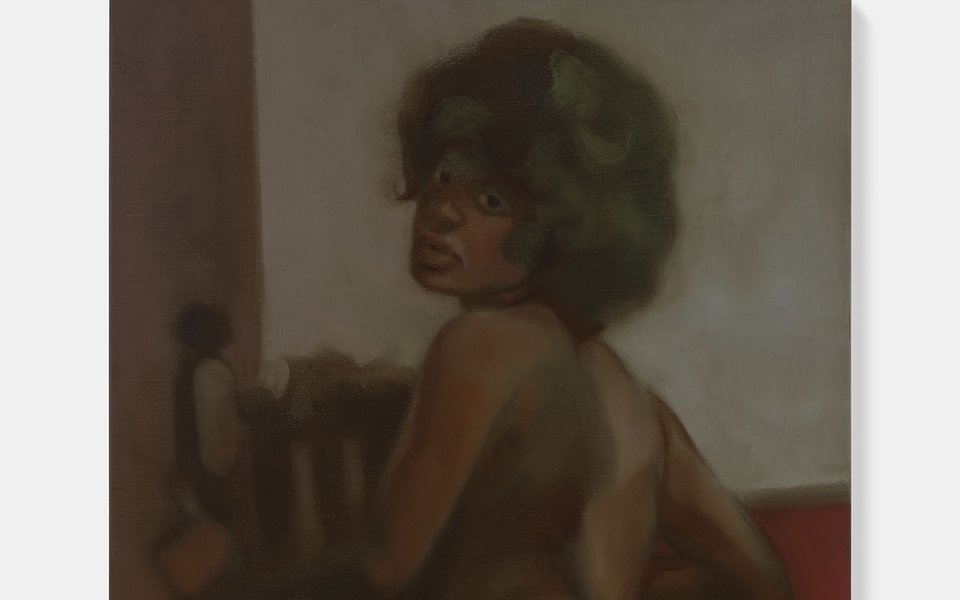 Portrait of a nude woman from behind. She kneels on a chair and looks back over her left shoulder.